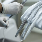 Mano con guante manejando instrumental dental esterilizado en Serviprodent, clínica dental en Valdemorillo