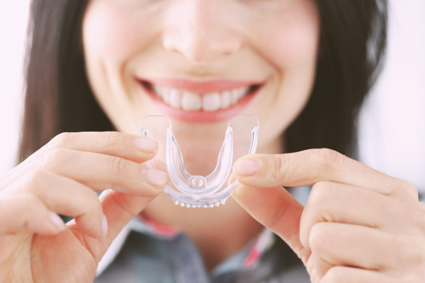 Férulas Dentales: Una Solución para el Bruxismo Mujer sosteniendo una férula dental para prevenir el bruxismo