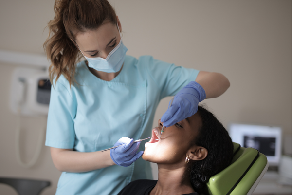 La mejor forma de prevenir el mal aliento Dentista examinando la boca de una paciente en el consultorio.